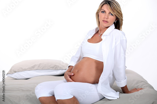 Pregnant blond woman sat in bed