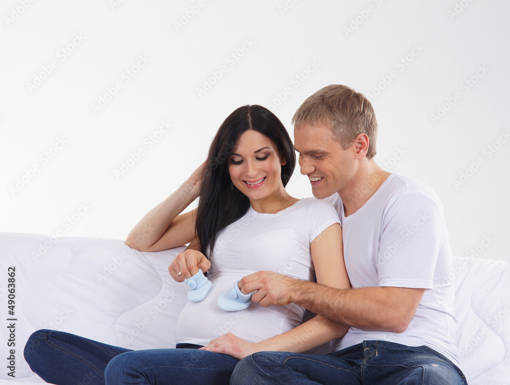 A young couple on a white sofa preparing for the baby A young couple on a white sofa preparing for the baby