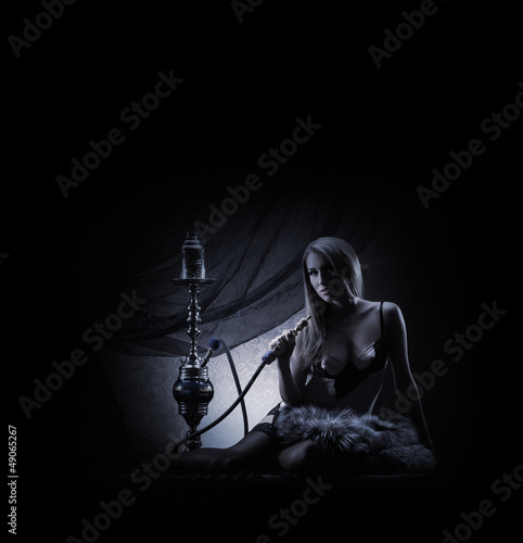 A young and sexy woman in lingerie smoking a hookah
