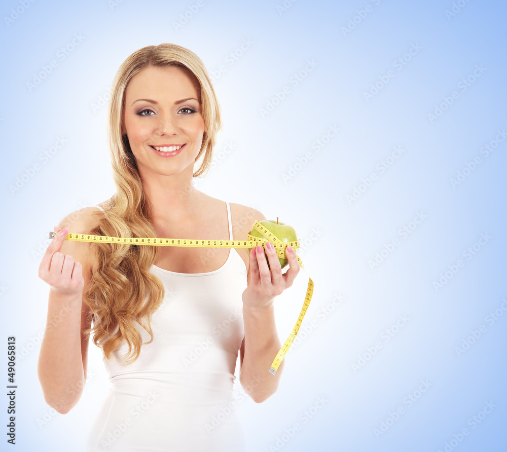 A happy blond woman holding a measuring tape and an apple A happy blond woman holding a measuring tape and an apple