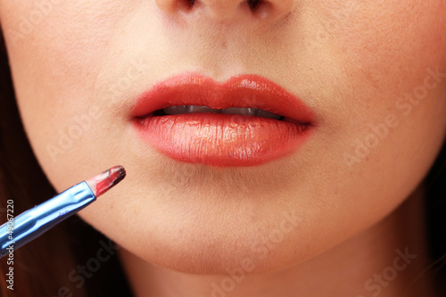 beautiful woman applying lip gloss  close up