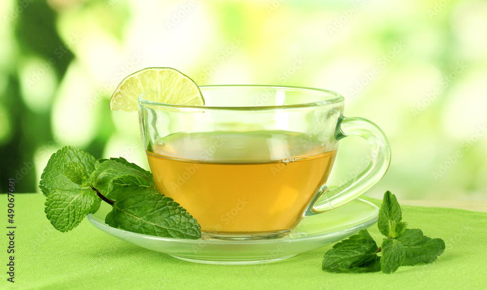 Cup of tea with mint on table on bright background Cup of tea with mint on table on bright background
