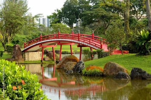 Curved red bridge over stream in Japanese Gardens, Singapore. #49068436