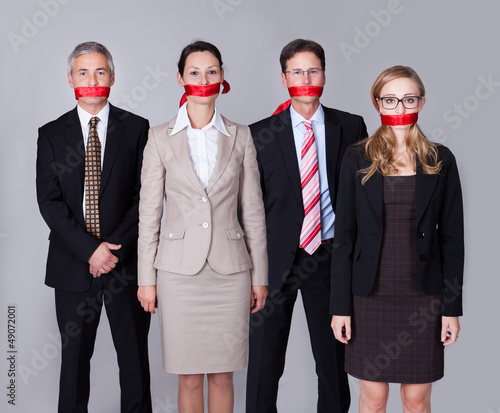 Businesspeople bound by red tape photo