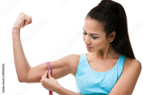 Tela Sportive woman measures her bicep with measuring tape