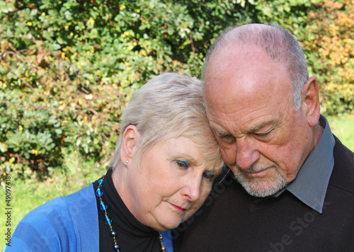 Beautiful old lady leaning on husbands shoulder in grief