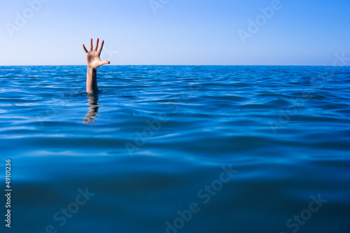 Help needed. Drowning man's hand in sea or ocean. photo