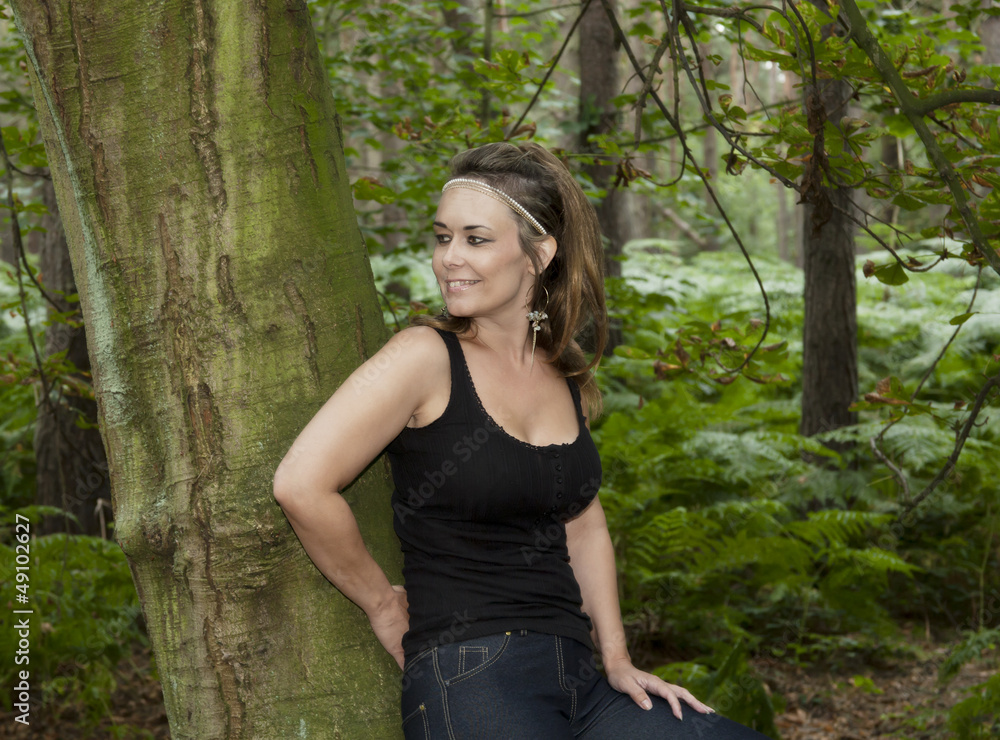 attractive woman in woodland setting leaning against a tree attractive woman in woodland setting leaning against a tree