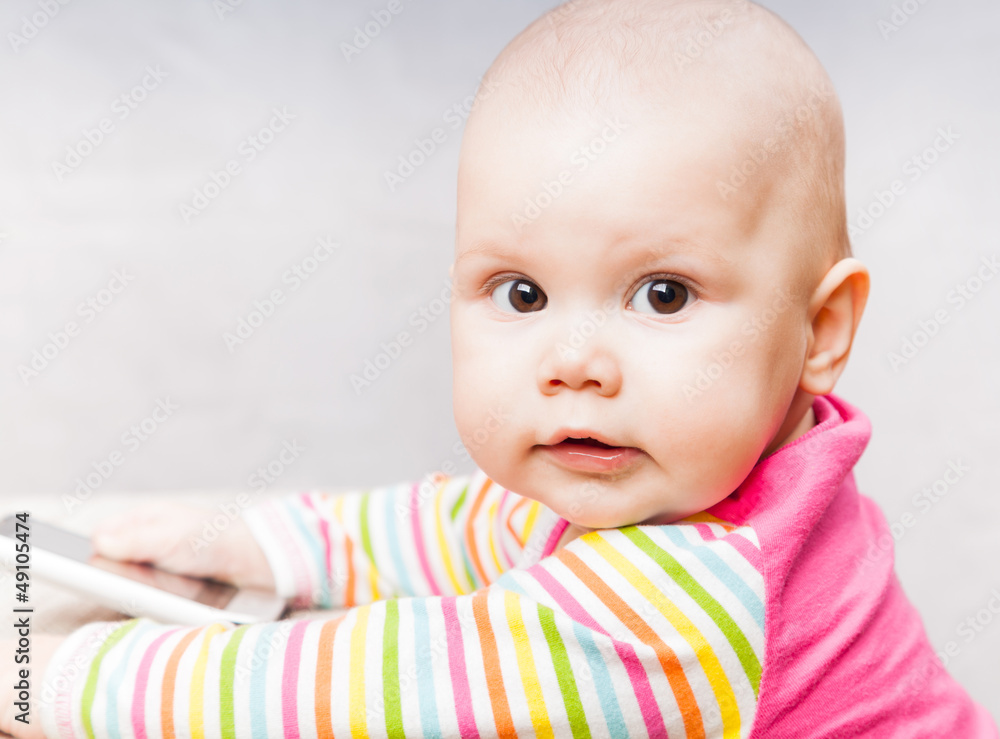 Little baby in colorful striped clothing with mobile phone