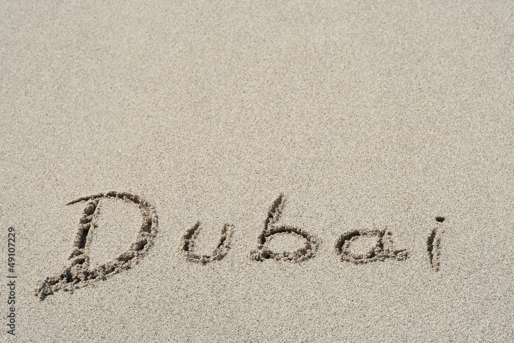 Fototapeta premium Conceptual handwritten text Dubai in sand