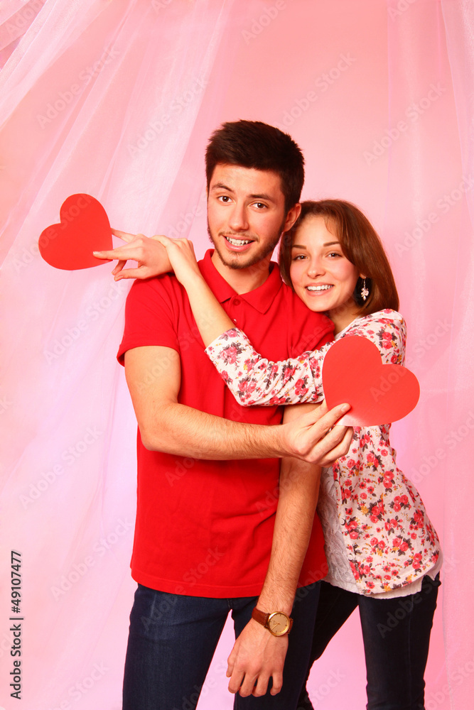 Happy couple with paper hearts on a background of pink tulle Happy couple with paper hearts on a background of pink tulle
