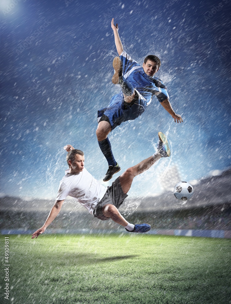two football players striking the ball two football players striking the ball
