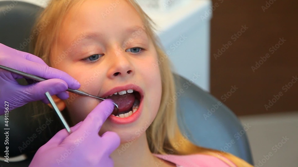Woman dentist diagnoses teeth of little girl patient Woman dentist diagnoses teeth of little girl patient