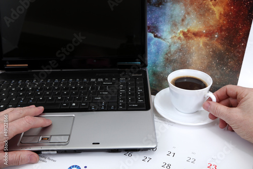 Laptop, dłonie i kawa na biurku.