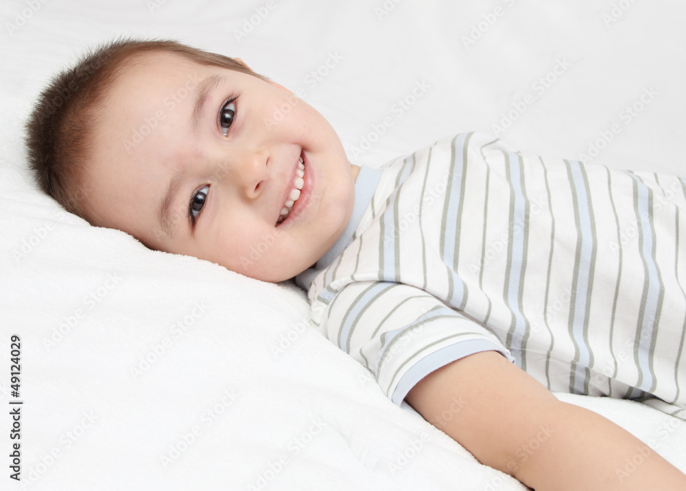 Happy child lies on white bed Happy child lies on white bed