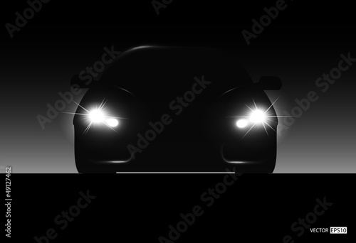 Silhouette of car with headlights on black background.