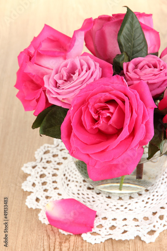 Beautiful pink roses in vase on wooden table close-up