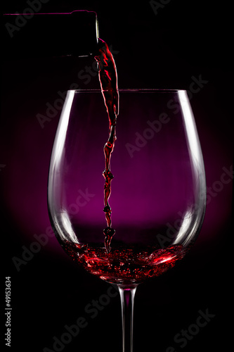 Fototapete Llenando la copa de vino sobre fondo negro
