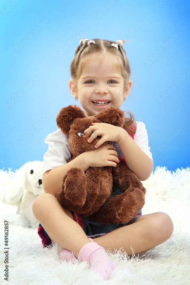cute little girl playing with toy bear, on blue background cute little girl playing with toy bear, on blue background