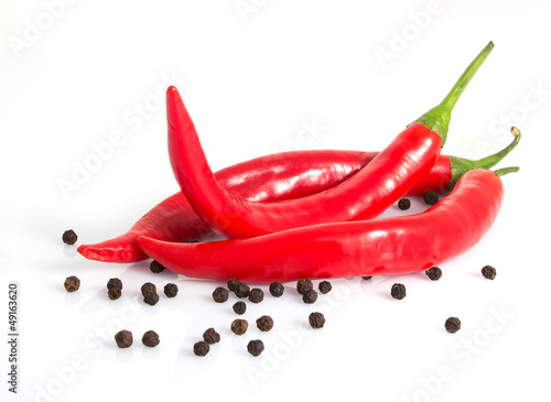 three red hot peppers and black peppercorns isolated