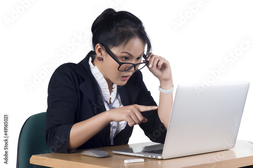 Business woman pointing at laptop's screen looking shocked and s