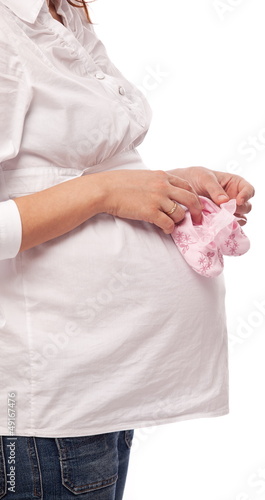 Pregnant woman keeping pink baby-shoes.