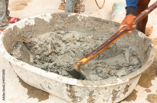 builder worker during using hoe to mix wet cement