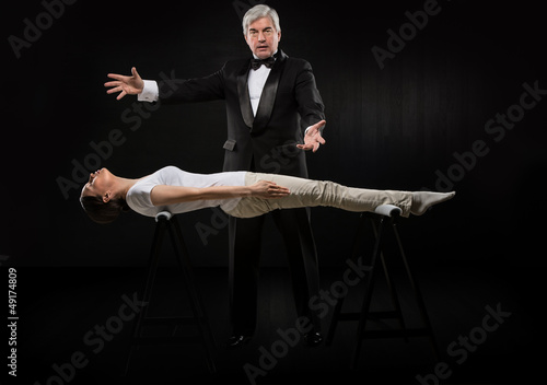 Papier peint Portrait of professional hypnotist on black background working w