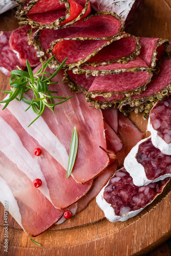 Foto Assorted cold cuts with rosemary on chopping board