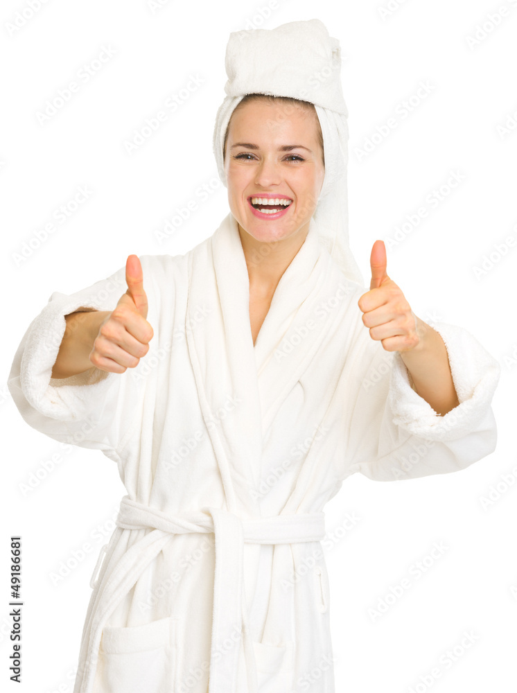 Smiling young woman in bathrobe showing thumbs up Smiling young woman in bathrobe showing thumbs up