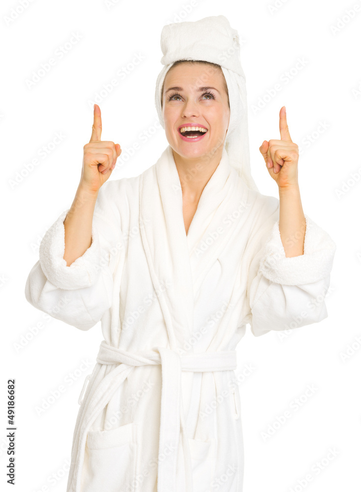 Happy young woman in bathrobe pointing up on copy space Happy young woman in bathrobe pointing up on copy space