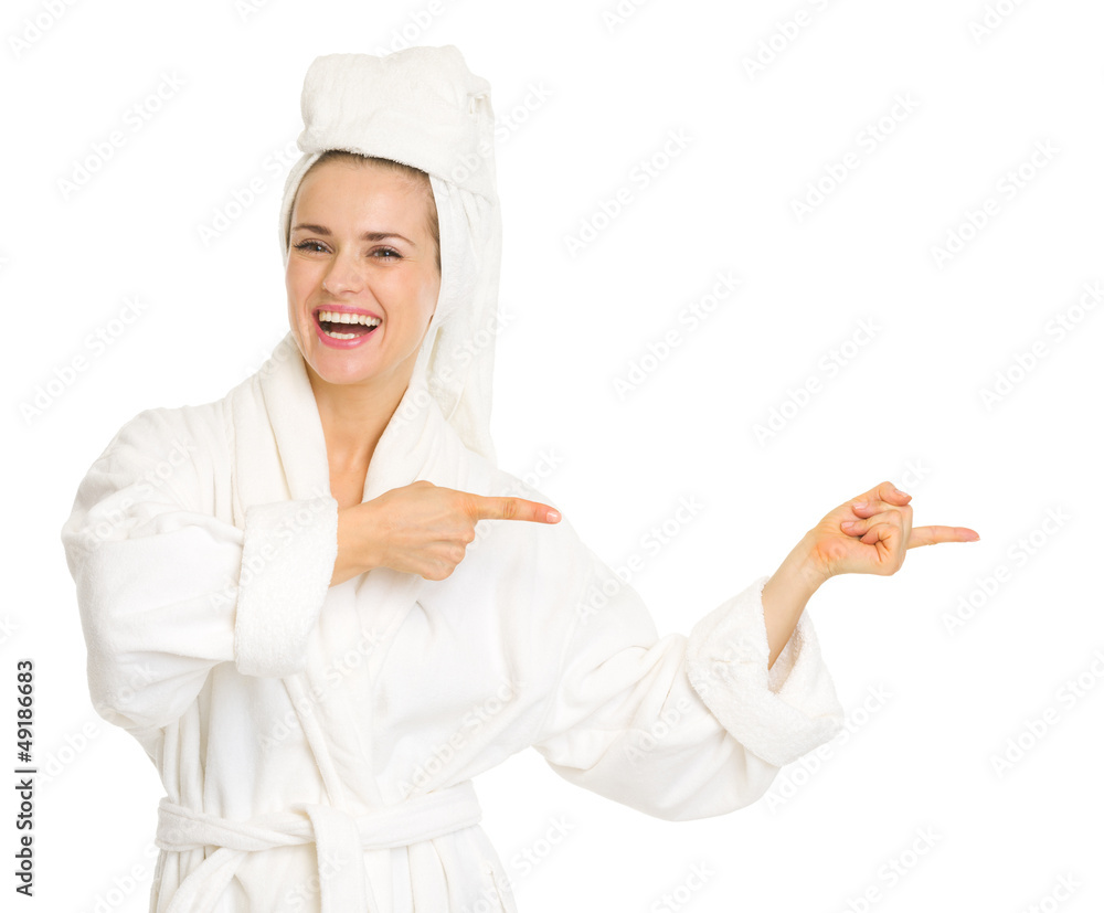 Smiling young woman in bathrobe pointing on copy space Smiling young woman in bathrobe pointing on copy space