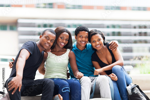 group of happy african college students sitting outdoors