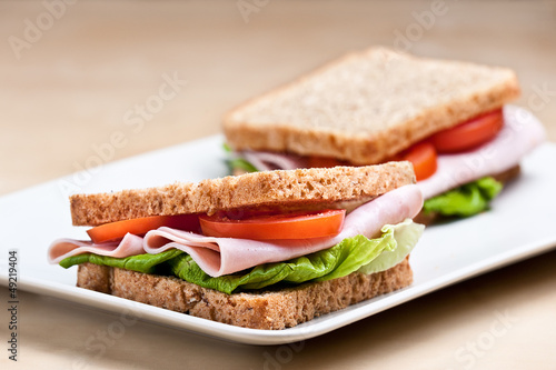 Ham sandwich on brown bread with tomatoes and lettuce.