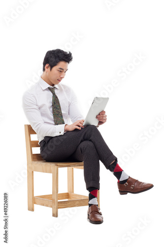 Young Asian business man using a pad PC sitting on the chair.