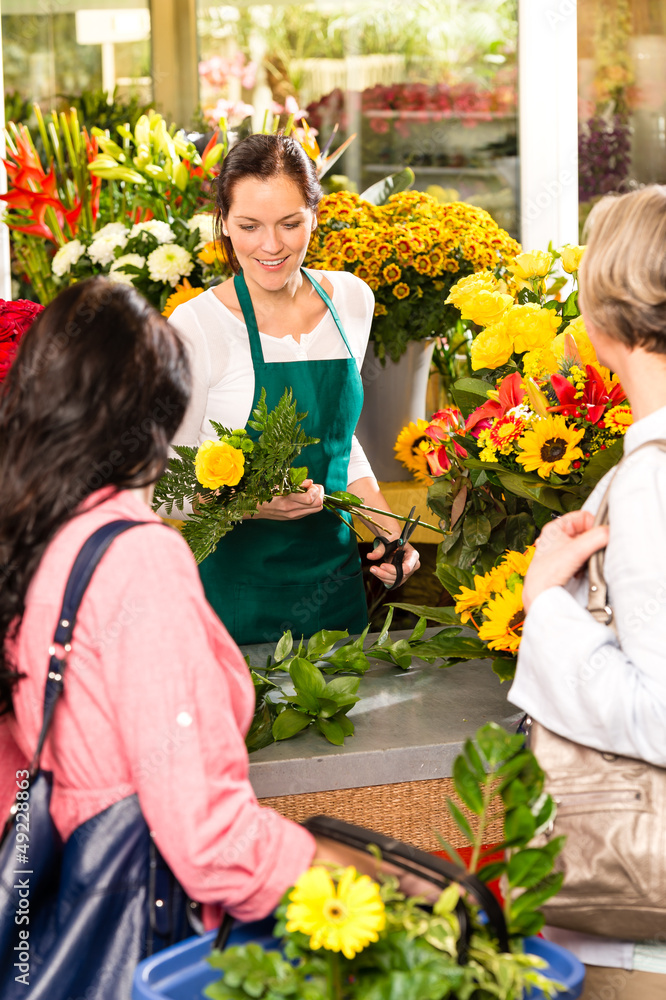Fototapeta premium Young woman florist cutting flower shop customers