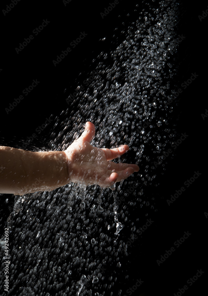 Fototapeta premium hand of baby reach to fresh water droplet from above on black ba