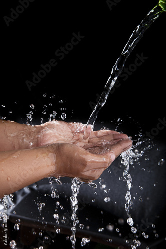 file of hand and pouring water splashing on black background