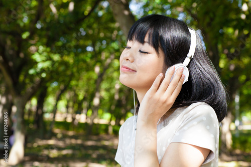 atractive asian woman listening music in the park
