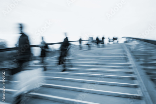 Motion blur and blue tint of people crossing bridge.