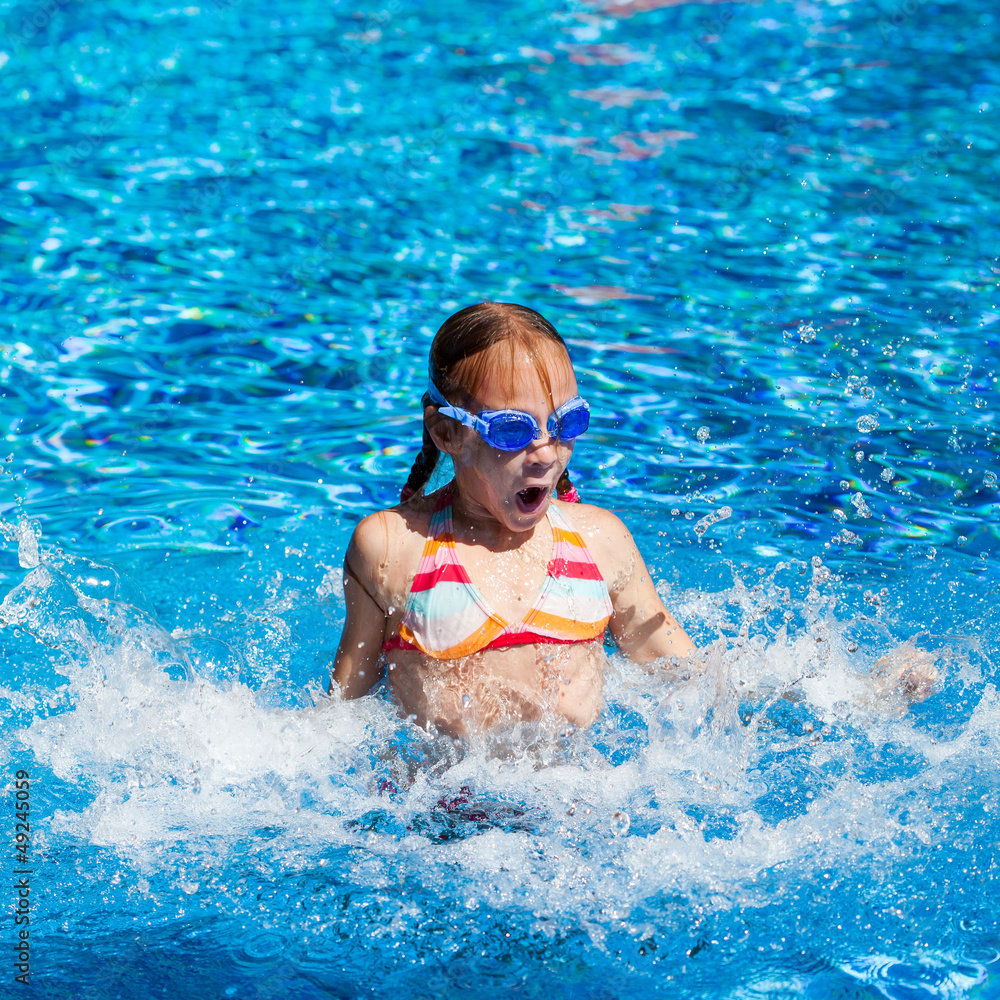 happy little girl splashing around in the pool