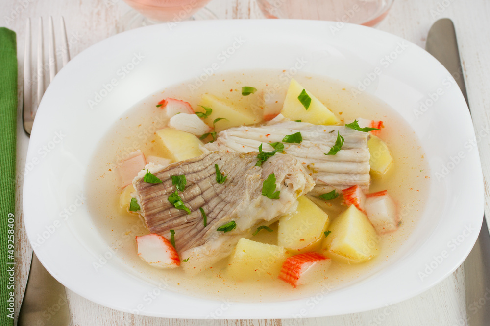 fish stew in the white plate with fork and knife