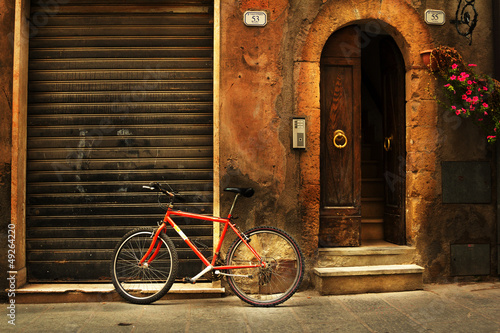 Old town alley and a red bicycle in Tuscany Italy