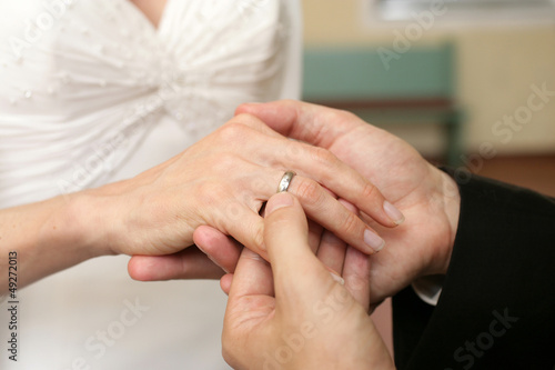 Braut streift Ihrem Braeutigam den Ehering ueber den Ringfinger