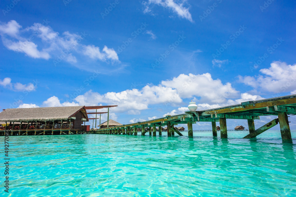 Wooden path to the bungalow above water on tropical island