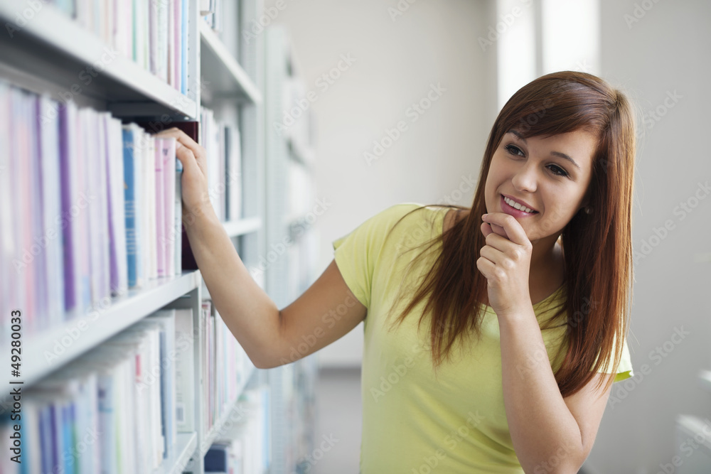 Beautiful student choosing book in library