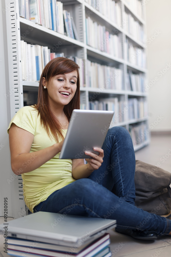 Happy student using digital tablet in library Happy student using digital tablet in library