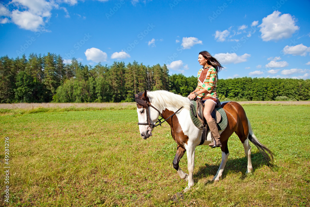 A young girl dressed as an Indian rides a paint horse