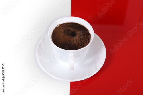 Kawa w białej filiżance na biało czerwonym tle.