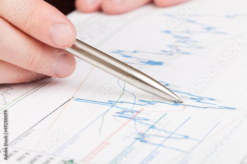 Businessman indicating with pen on diagram of financial report